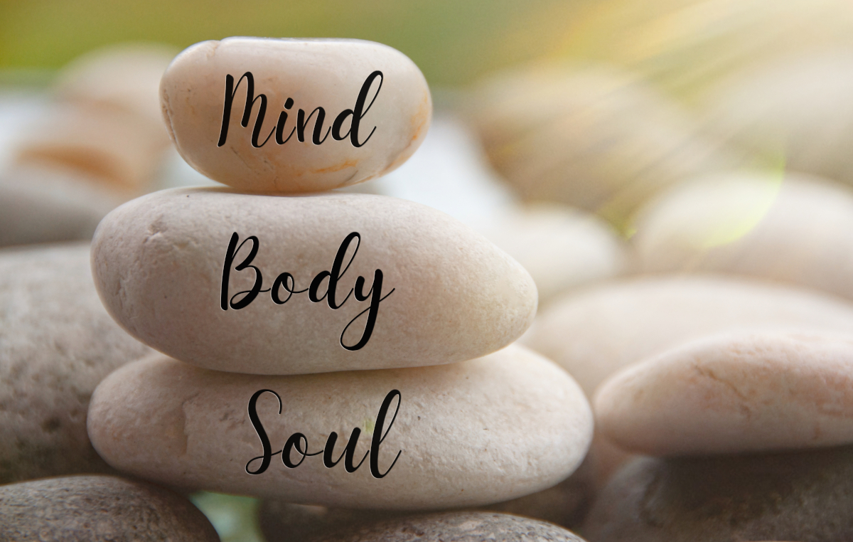 Light shining on zen stones with words Mind, Body, Soul on blurred background. Customize space for text or ideas